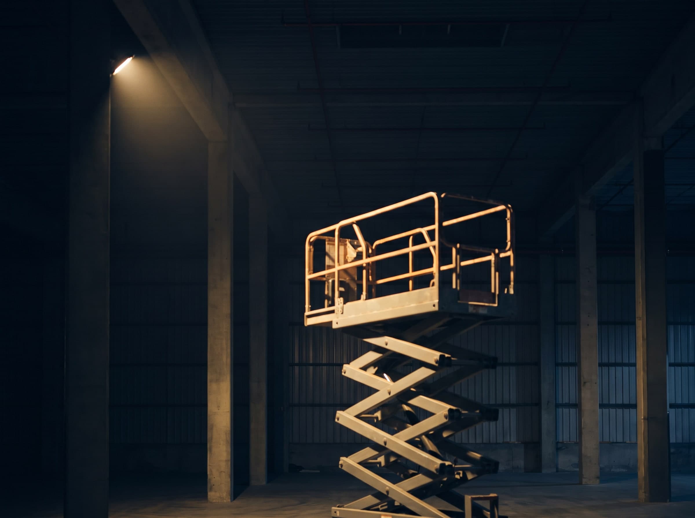 Half-extended scissor lift in a tall, empty hall